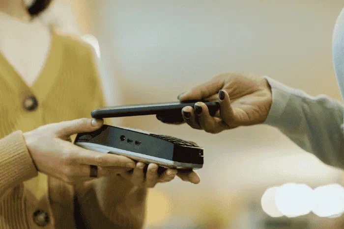 A small business owner reviewing digital expense tracking on a phone and laptop