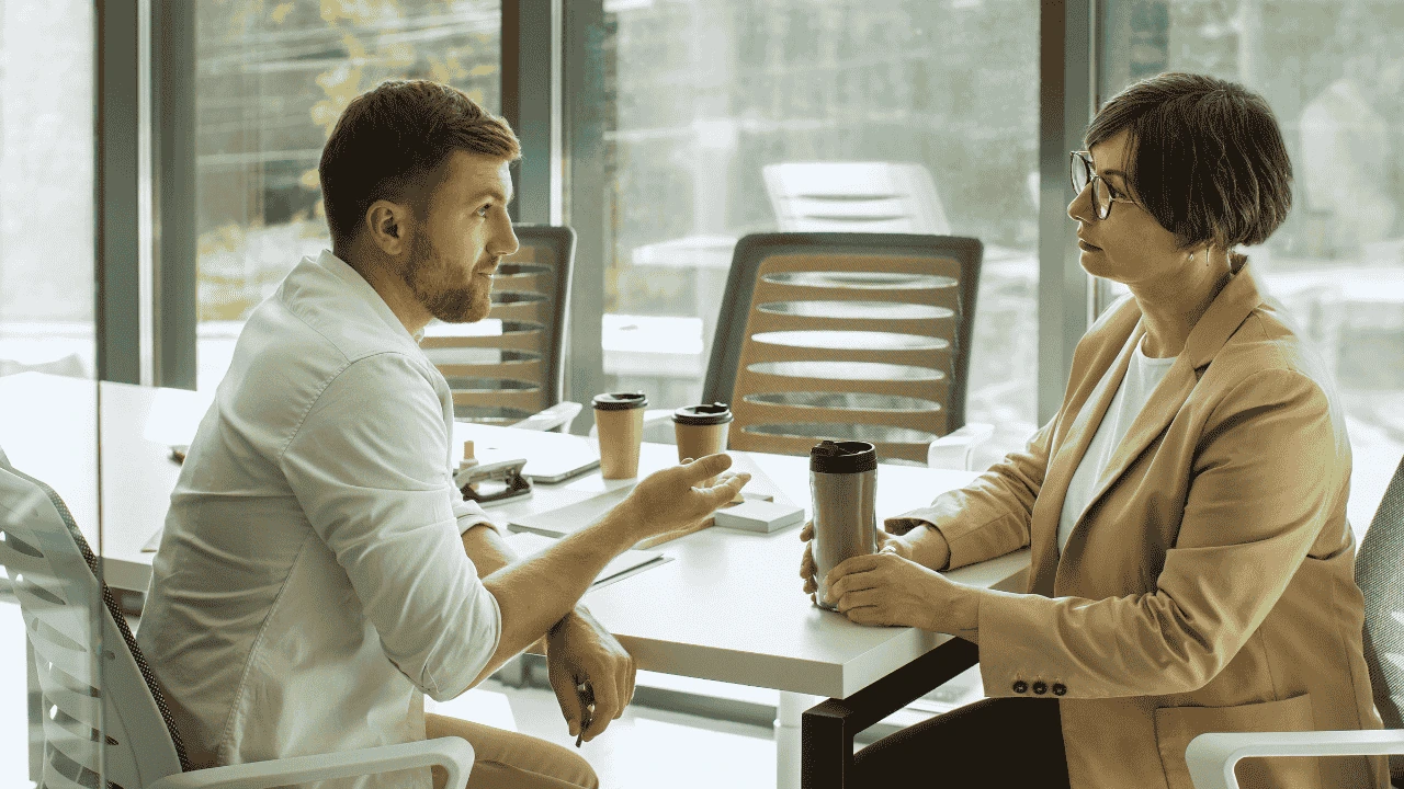 Two professionals discussing sustainable business systems in a modern office setting