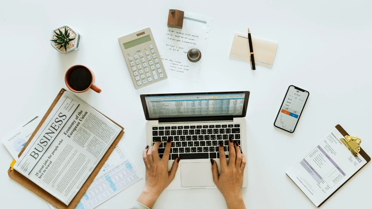 Overhead view of a workspace with laptop, financial documents, and coffee, ideal for business finance blogs