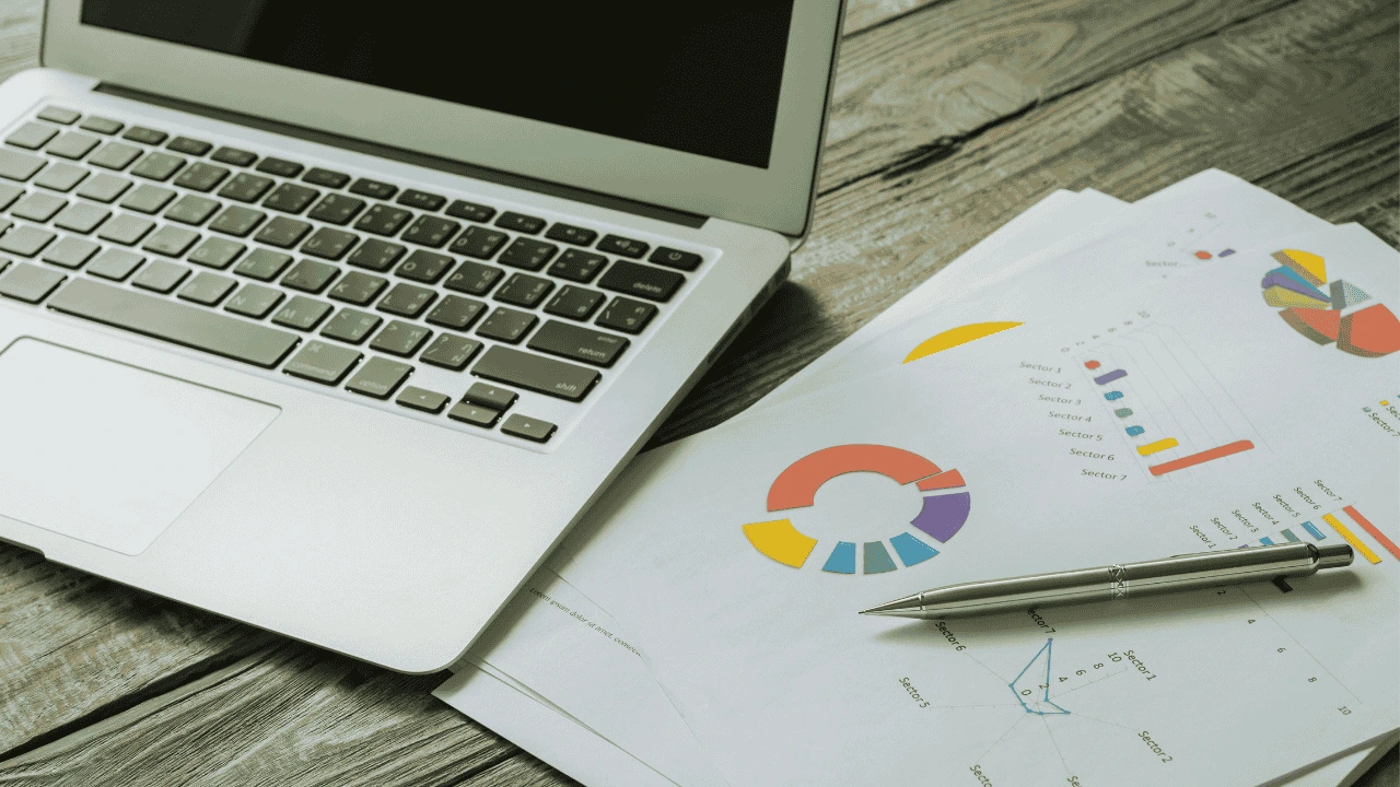 Laptop and financial reports with charts and graphs used for marketing spend accounting in Ireland.