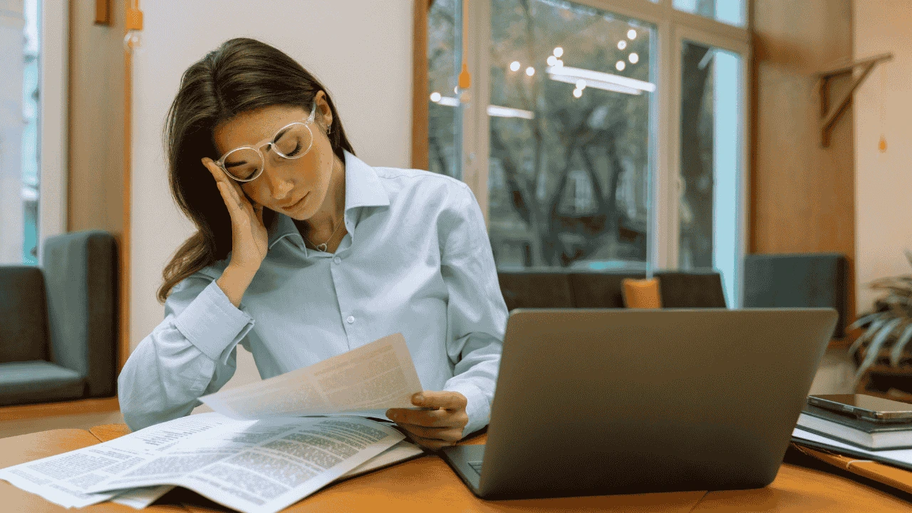 Stressed businesswoman reviewing financial documents instead of using outsourced bookkeeping in Ireland