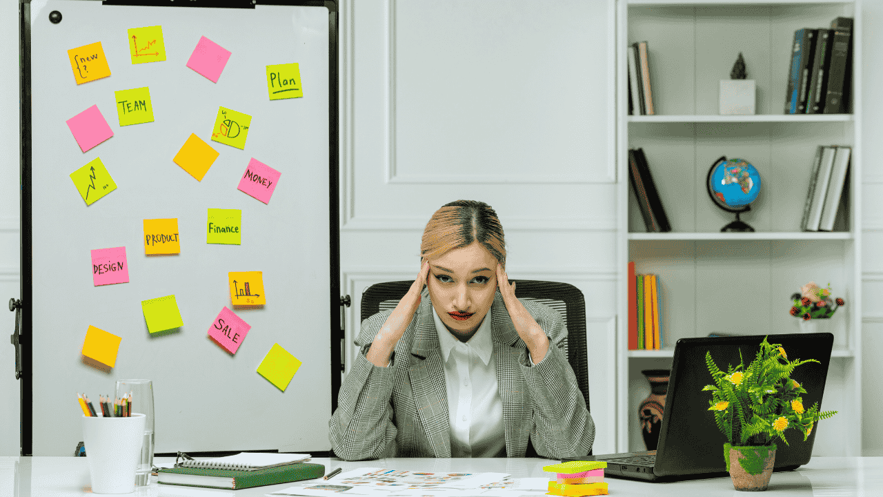 A stressed business owner surrounded by notes and tasks, considering hiring decisions for small businesses.