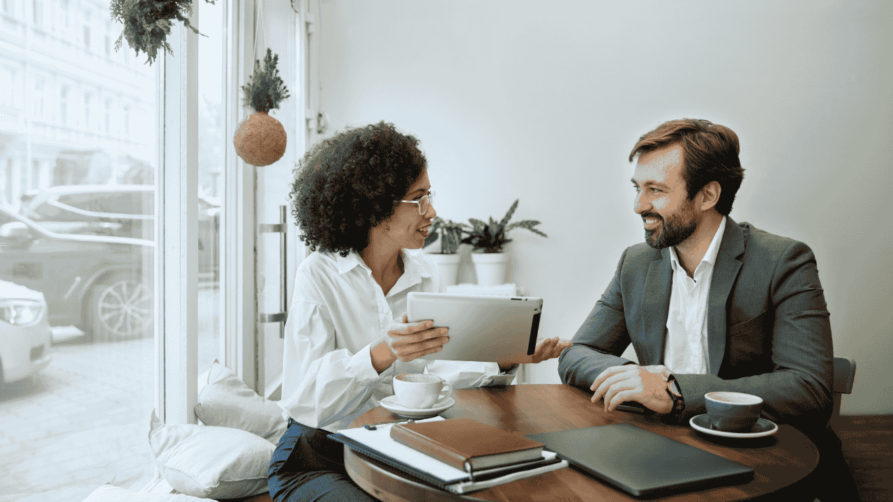 Two business professionals discussing finance for new business owners over coffee in a modern café.