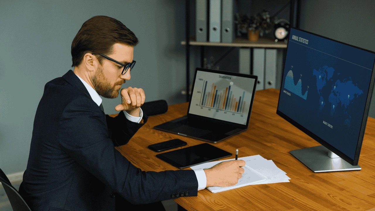 Business professional reviewing financial reports on multiple screens — representing when to hire a bookkeeper in Ireland.
