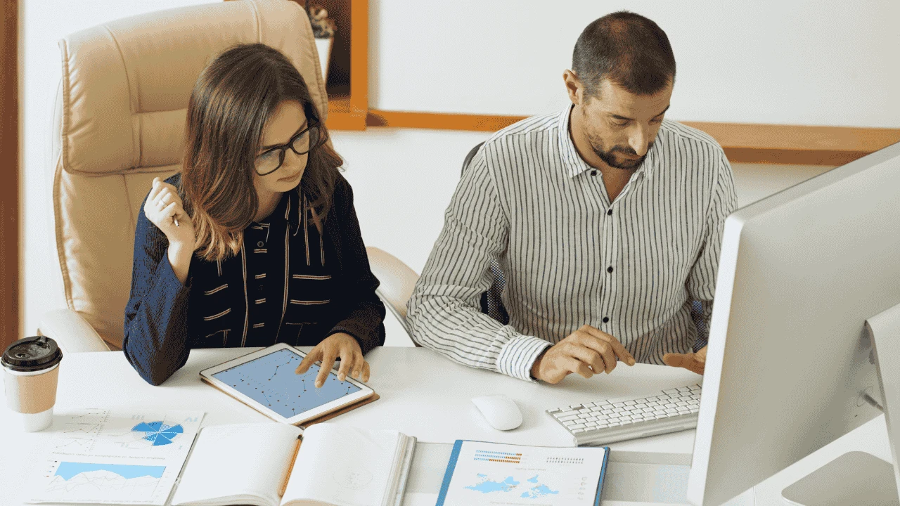 Two professionals reviewing charts and financial records to understand how VAT works for Irish service businesses