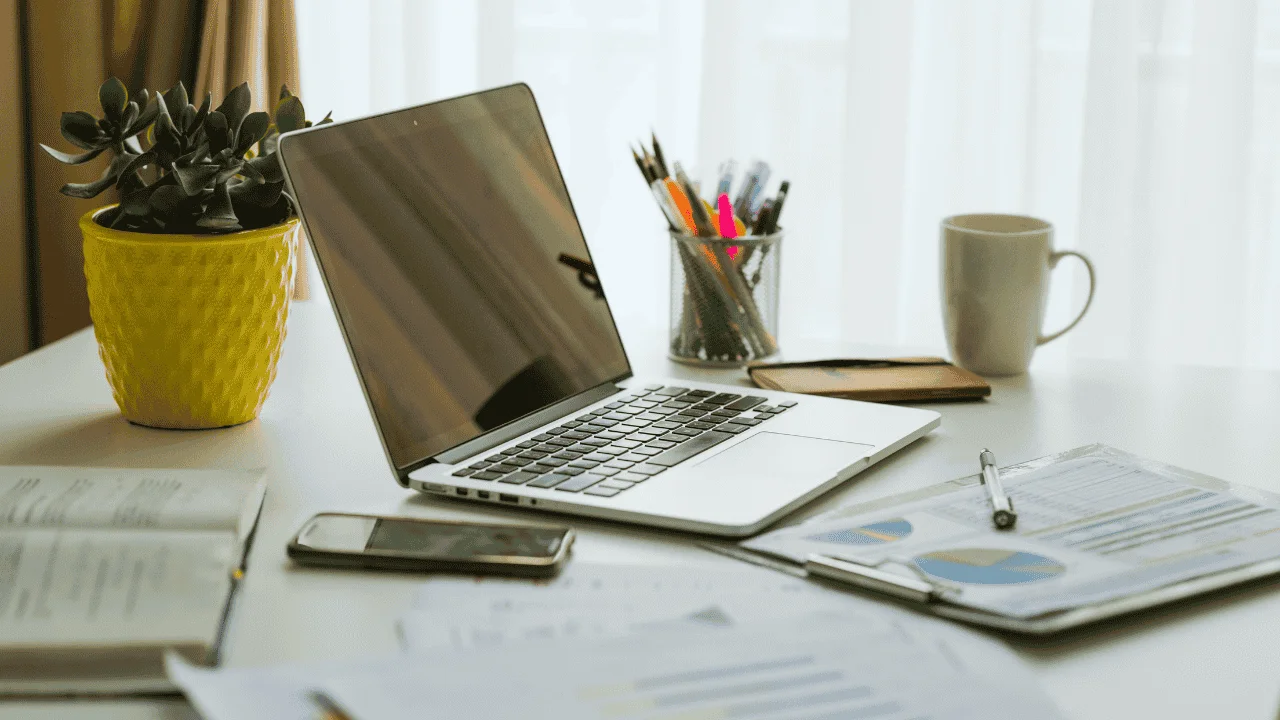 Laptop with financial reports and stationery on desk — representing structured bookkeeping process in Ireland